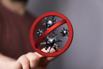 Hand holding a red sign symbolizing stopping the virus and the COVID-19 pandemic. Concepts of...