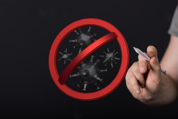 Concept image depicts stopping the spread of the virus with the stop sign.  Hand holding the sign over virus c
