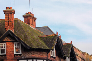 Beautiful Oxford architecture. Old brick building with fairytale moldy roof. Clay chimney pots on the top of red brick chimney stack of the English building.