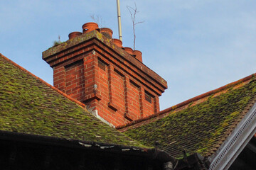 Beautiful Oxford architecture. Old brick building with fairytale moldy roof. Clay chimney pots on the top of red brick chimney stack of the English building.