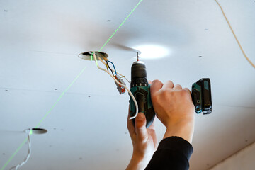 Interior construction scene with plasterboard panel, laser line shows exact alignment, electrical installation prepared with visible cables and holes