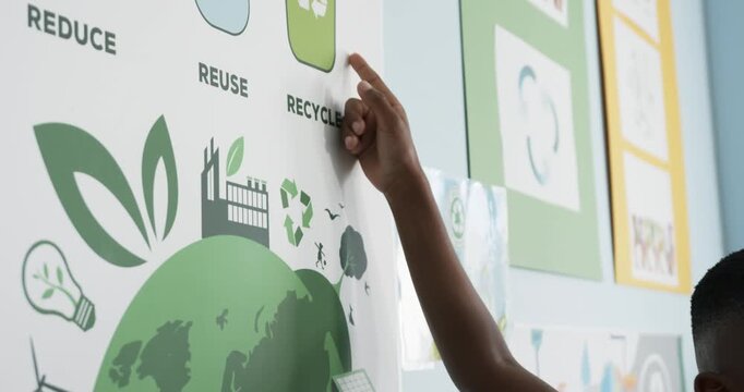 Seeing recycling icon student is reaching up pressing poster on school wall promoting recycling