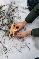 a man lights a fire in winter