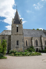 Historic Stone Church With Clock Tower, Gothic Windows And Garden Courtyard Under Bright Blue Sky