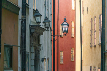 View of a vibrant street with colorful buildings and vintage lamps casting soft light in the old town, Gamla stan, Stockholm, Sweden.