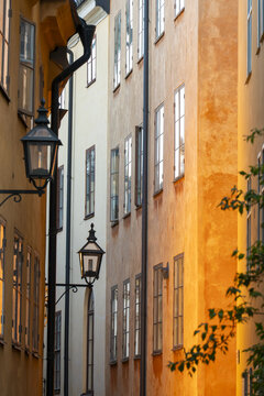View of sunlight bathes the textured facades of old buildings, casting long shadows and highlighting the vintage street lamps, Gamla stan, Stockholm, Sweden.