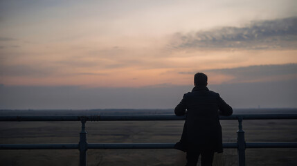 Obraz premium Man contemplating life at dusk with serene landscape view