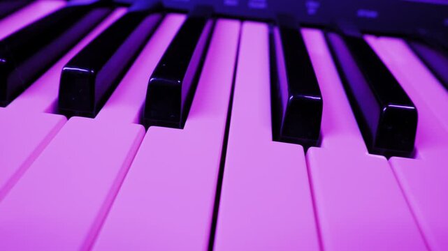 Synthesizer keyboard's glossy black and white keys reflect colorful flashing lights. Low angle close up captures a dynamic, vibrant party or concert atmosphere.