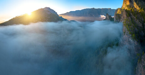 Aerial sunrise view of a volcanic mountain amphitheater filled with a sea of clouds in Parque Nacional de la Caldera de Taburiente, ideal for: adventure travel marketing, premium wall art.