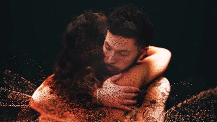 Tender moment of a man and woman embracing each other. Their bodies, made of glowing particles, slowly dissolve in a loving, warm hug
