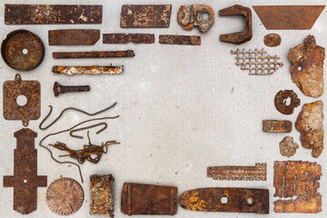 A group of various old rusty bits and pieces arranged on a concrete surface. Old rusty nuts, bolts, nails and other parts flay lay on gray background.