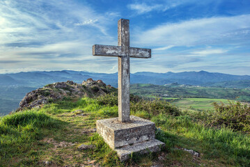 stone cross overlooking the valley in the mountains of Abruzzo in Italy under a cloudy sky