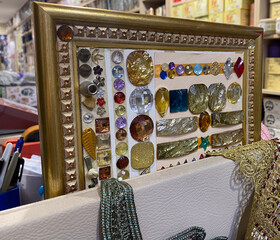 Colorful gemstones and beads in ornate frame on craft store display shelf