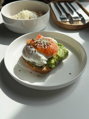 Toast with smashed avocado, poached egg and lightly salted fish. Healthy food concept. Handmade smartphone photo, selective focus, harsh sunlight, non AI