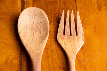 Two handmade wooden kitchen utensils placed vertically on a natural wooden surface. Minimalist...