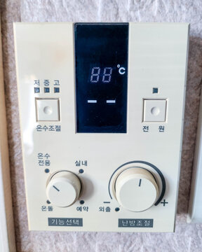 Close-up of old analog gas boiler heating controller on the wall in Korea. Korean text interface with dial and buttons. Concept for winter heating costs and Ondol system.