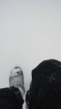 Close-up of a man's legs walking through thick snow wearing warm Ugg boots