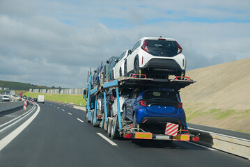 car transporter with 2 rows of new small cars on the trailer, german freeway