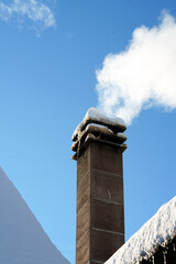 Brick chimney on a snow-covered roof against a cloudy winter sky