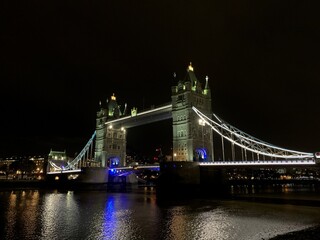 Obraz premium LONDON, UK, October 22, 2019 London Tower Bridge lit at night with reflections on the River Thames, dark sky and city lights in the background.