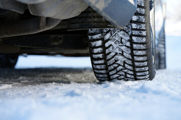 Close-up of car winter tire with snow on a frozen road