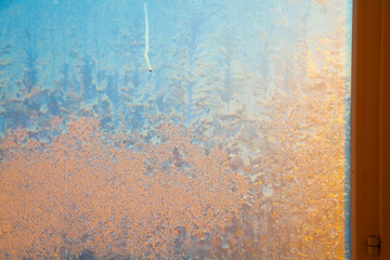 Golden sun shining through frozen window