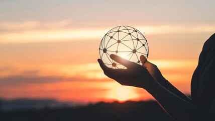 Person holding geometric wireframe globe at sunset with vibrant sky