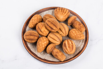 Cookies in the shape of nuts, cones, mushrooms and shells. Stuffed with boiled condensed milk. On a plate. White background. Close up
