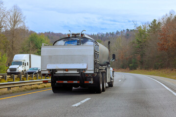 Trucks travel down American highway lined with along roadside hills
