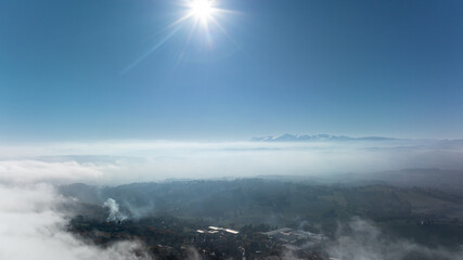 Fototapeta premium Aerial drone photograph revealing a stunning landscape of rolling hills and cultivated fields in the Marche region of Italy, partially covered by soft morning fog.