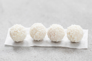 Coconut dessert candy balls with whole almonds inside. On paper. On a light background. Close-up	