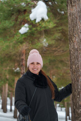 Woman smiling in winter forest wearing pink beanie