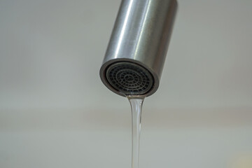 Close up view of a metal faucet with water dripping from its spout. selective focus