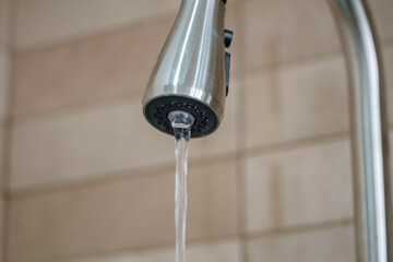 Close up view of a metal faucet with water dripping from its spout. selective focus