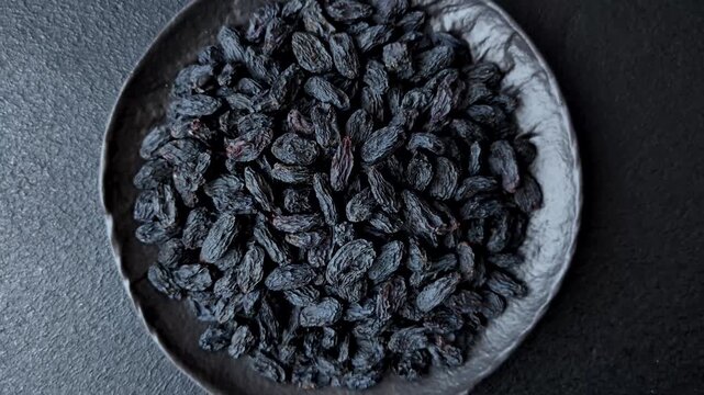 Sweet, dry black or blue raisins made from grapes are a healthy and nutritious food. Black raisins as a food background for your design