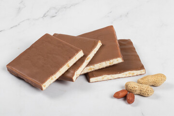 Nougat with peanuts in milk chocolate. White background. Close-up