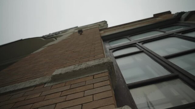 The facade of a historic brick building with stucco. Bottom view. Filmed in motion