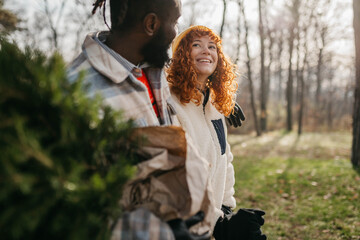 Young couple is packing Christmas tree on the car