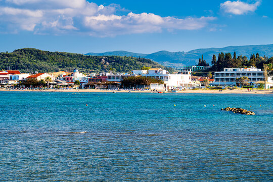Sidari Beach with tourists and umbrellas on green mountainous island Corfu, Greece. One the most beautiful islands in Ionian Sea.