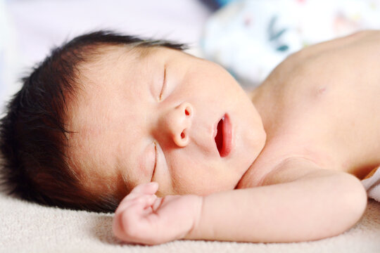 Sweet newborn baby sleeping with opened mouth.