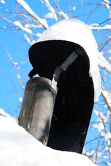 Metal chimney on a roof covered with thick white snow under blue sky