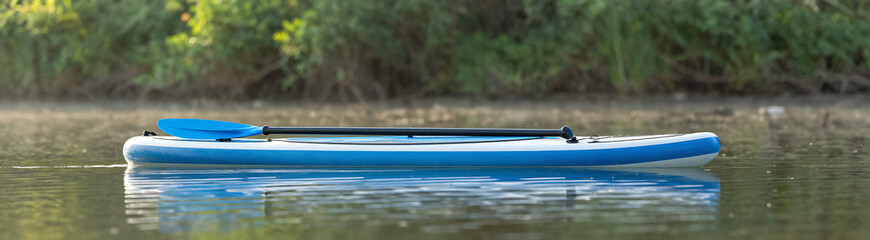 serene blue paddle lies horizontally surface tranquil lake surrounded lush green foliage gentle ripples soft morning