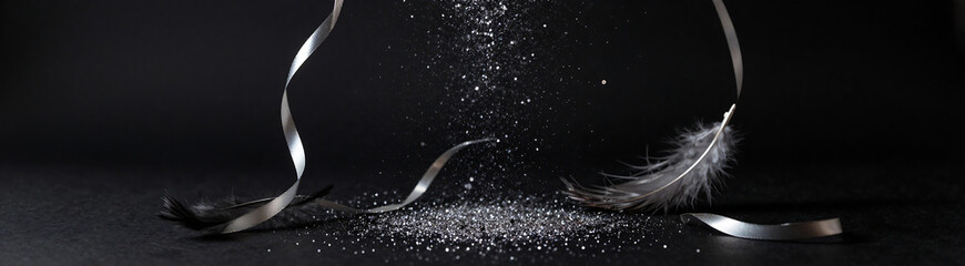 sprinkle glitter dust metallic ribbons soft feathers cascade matte black backdrop set dramatic