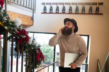 Man multitasking working remotely talking on smartphone in cafe