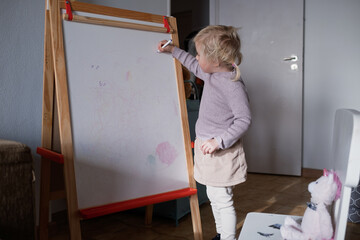Cute four year old blonde girl playing teacher and teaching numbers to her stuffed toy.