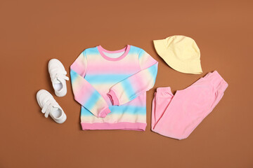 Stylish child clothes and shoes on brown background, flat lay