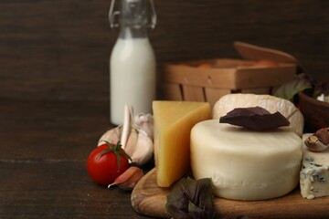 Different fresh dairy products, tomato, basil and garlic on wooden table, closeup. Space for text