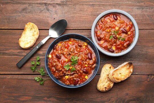 Delicious chili con carne served on wooden table, flat lay