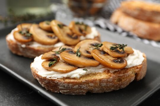 Tasty bruschettas with cream cheese, mushrooms and thyme on table, closeup