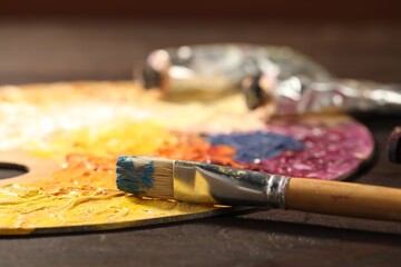 Fototapeta premium Palette with watercolor paints and brush on wooden table, closeup